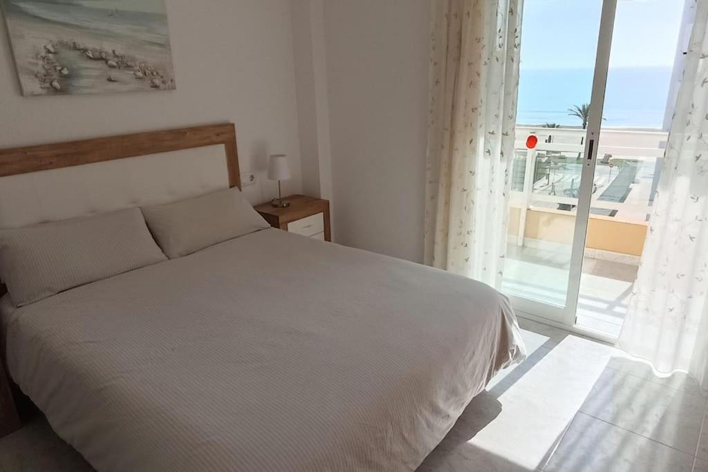 1 dormitorio con cama blanca y ventana grande en Apartamento céntrico en la playa con piscina., en Peñíscola