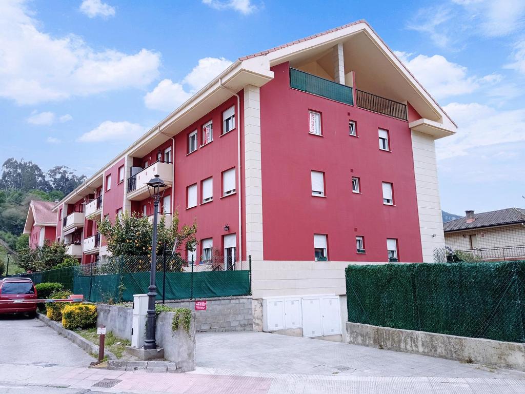 a red and white building with a car parked in front at APARTAMENTO LAS FRAGUAS in Ampuero