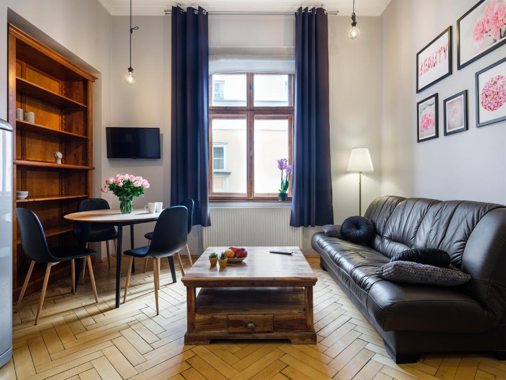 a living room with a leather couch and a table at CracWoW Market Squere Apartment in Krakow