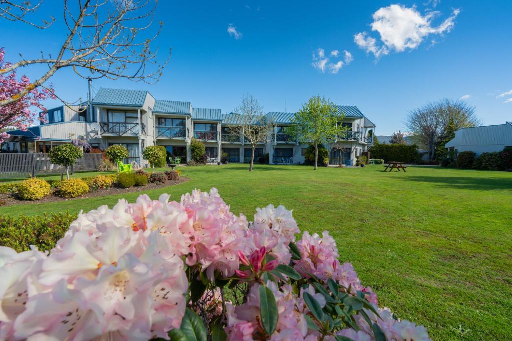 a large building with pink flowers in a park at ASURE Explorer Motel & Apartments in Te Anau