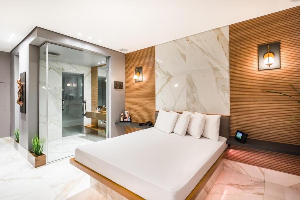 um quarto com uma cama branca e uma casa de banho em Motel Mood em São Paulo