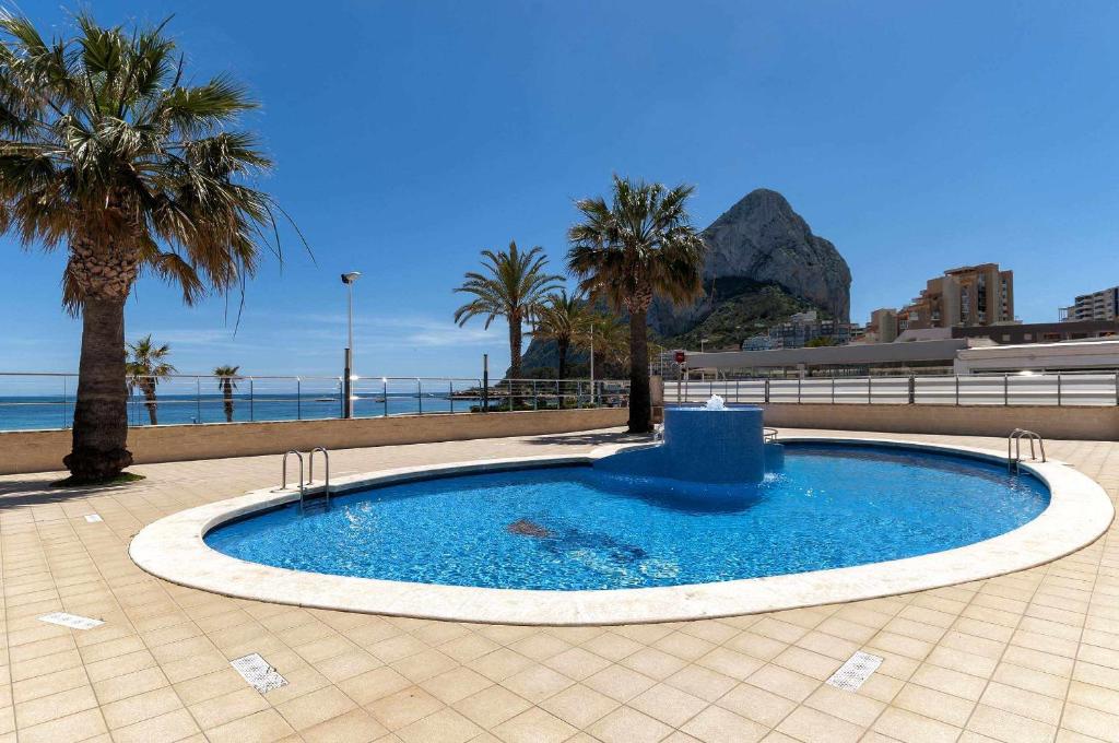 una gran piscina con palmeras y el océano en MODERNO apartamento, 3 habitaciones, 1ª LINEA playa, GARAJE, en Calpe
