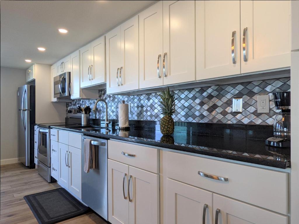 a kitchen with white cabinets and black counter tops at Sea Club Condo #32 in Clearwater Beach