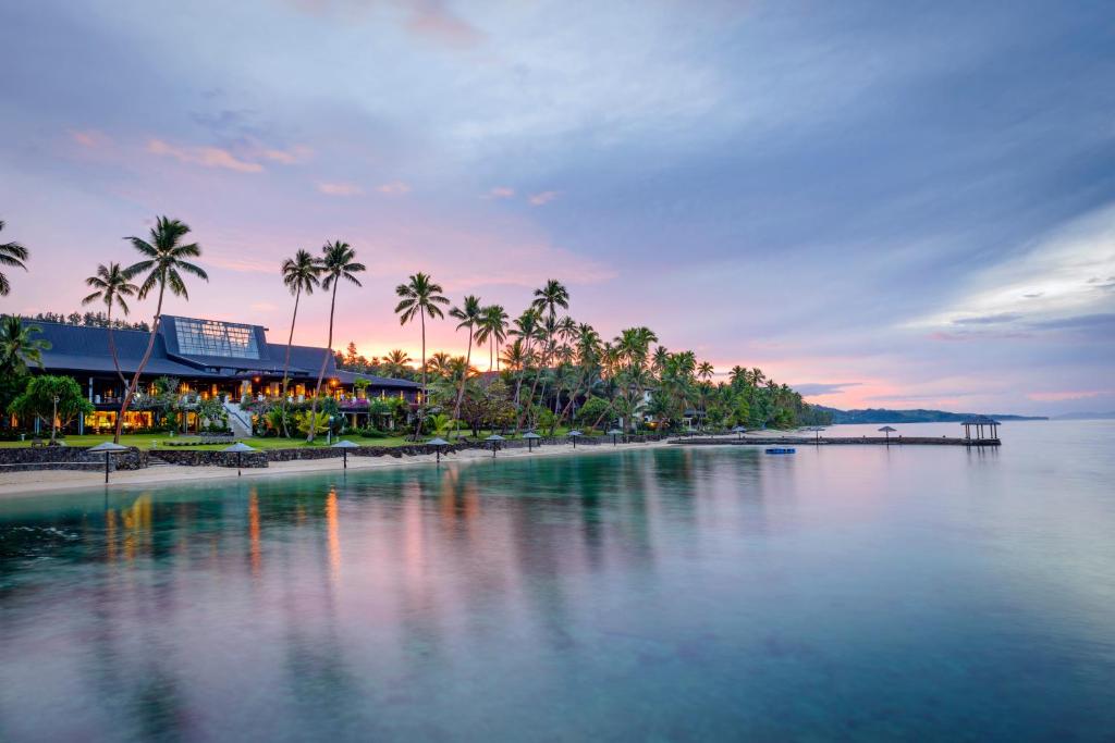 a large body of water with palm trees and a beach at The Warwick Fiji in Korolevu