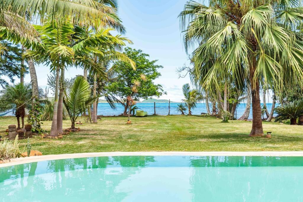una piscina frente a un complejo con palmeras en THE VILLA BY THE SEA Nouvelle-Caledonie, en Mont-Dore