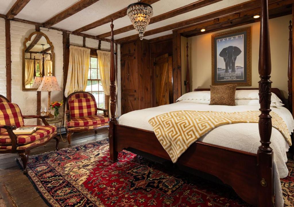 a bedroom with a canopy bed and two chairs at Prospect Hill Inn & Restaurant in Zion Crossroads