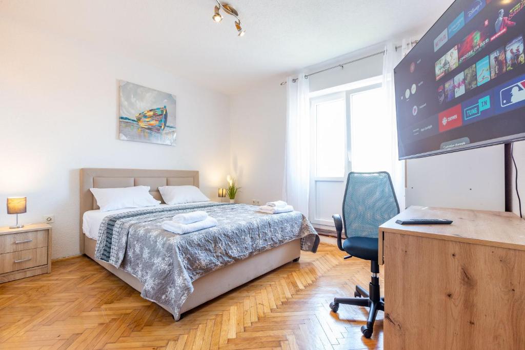a bedroom with a bed and a desk and a tv at Bobo central 2BR apartment in Zadar