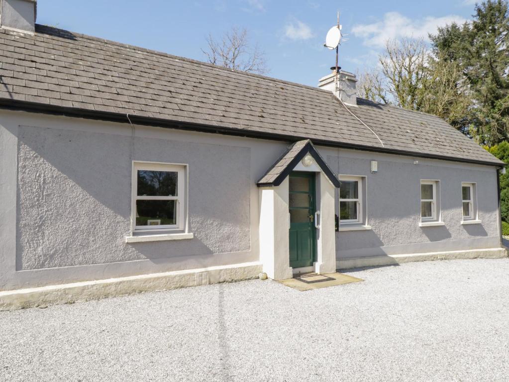 a small white building with a green door at Rambler's Rest in Manorhamilton