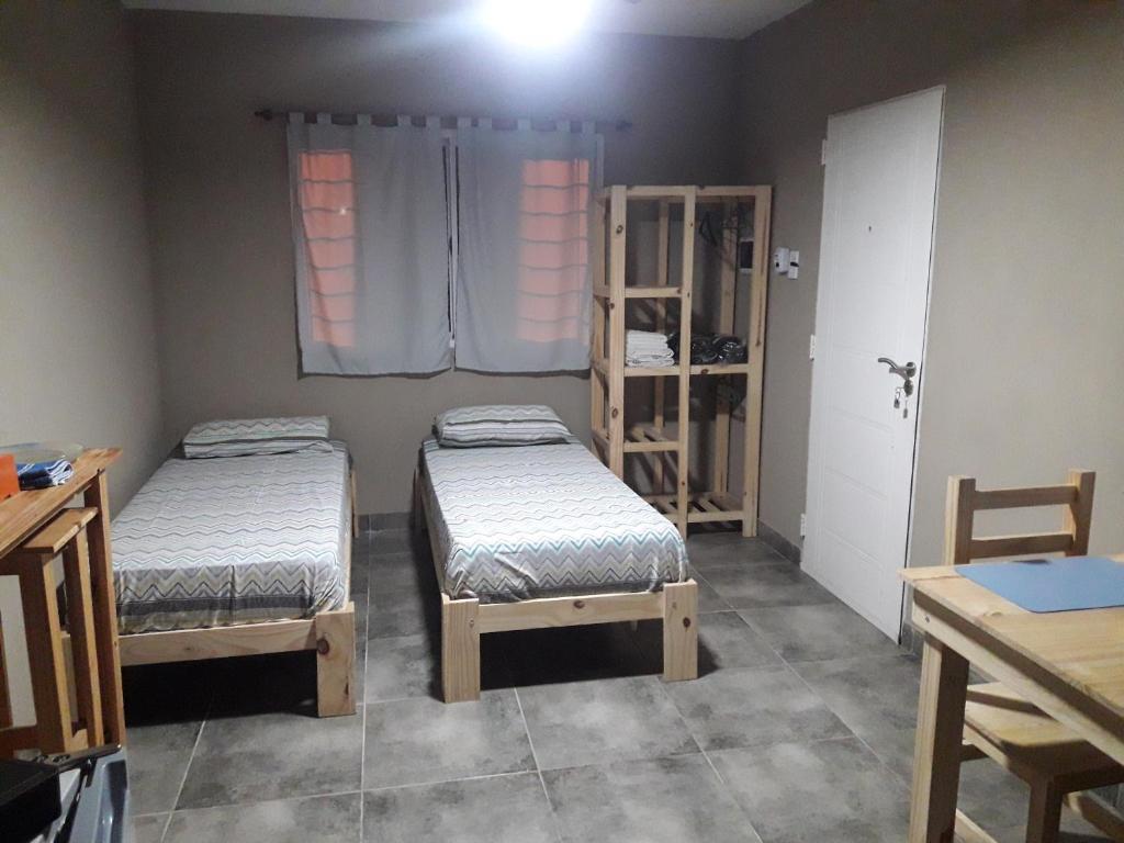 Habitación con 2 camas, mesa y ventana en Cabañas Samay en Funes