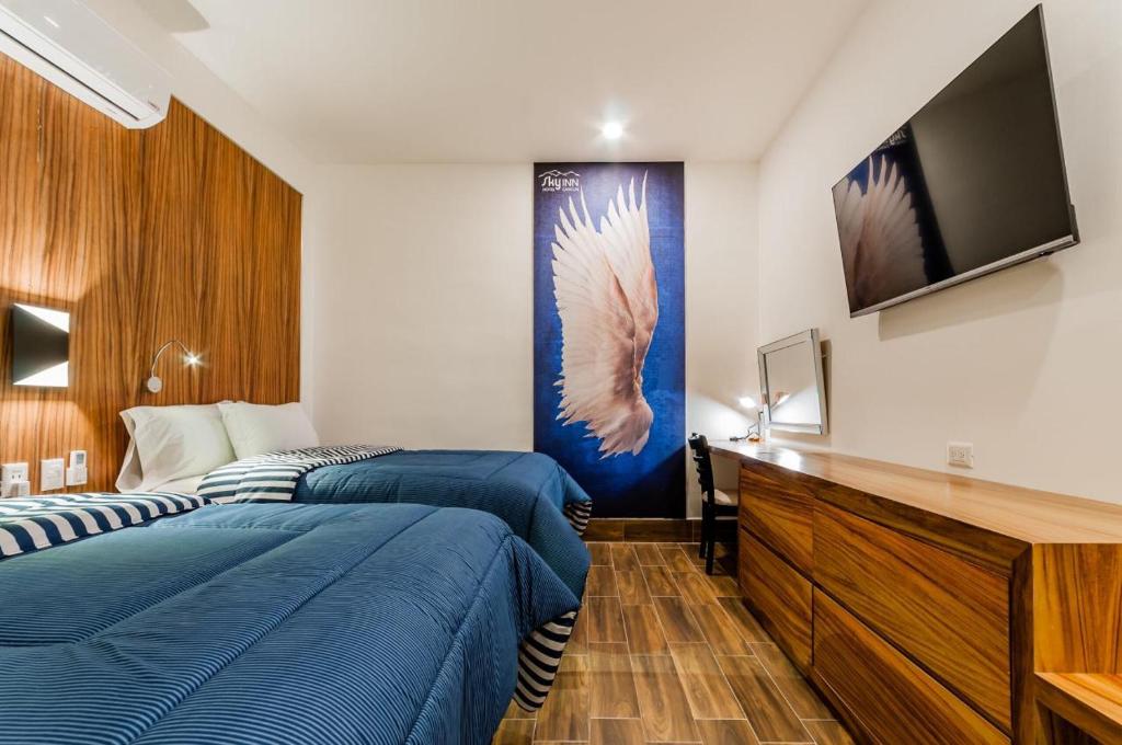 a hotel room with two beds and a flat screen tv at Sky Inn Cancun in Cancún