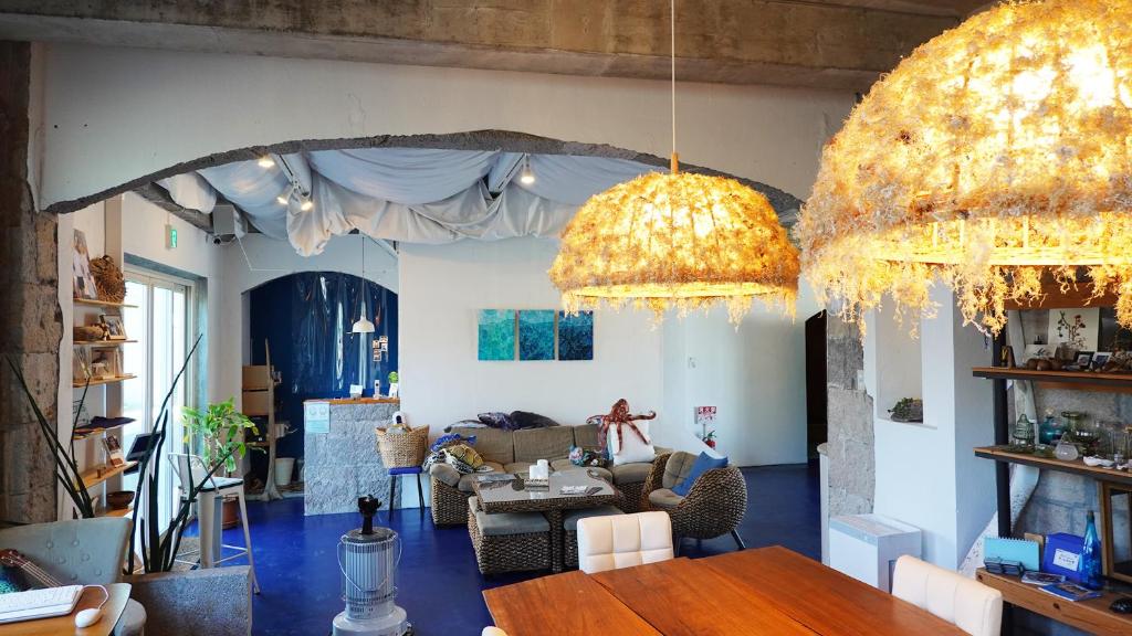 a living room with two chandeliers and a table at Hostel NABLA in Niijimamura