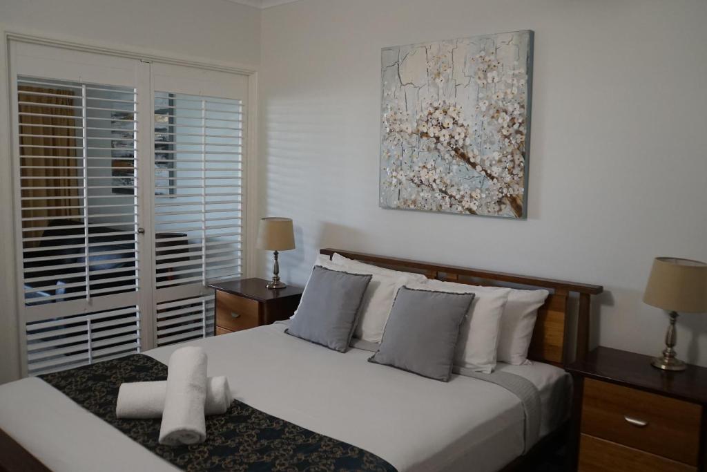 Airlie Seaview Apartments في شاطئ إيرلي: غرفة نوم بسرير ابيض ولوحة على الحائط