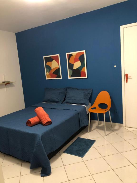 Dormitorio azul con cama y silla naranja en Apartamento Auge da Bahia en Salvador