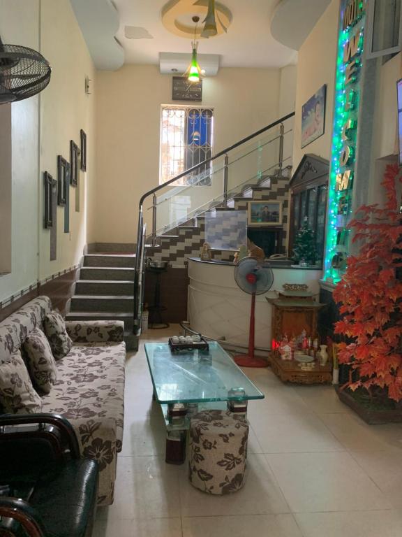 ein Wohnzimmer mit einer Couch und einem Tisch und einer Treppe in der Unterkunft Nhà nghỉ Hoàng Anh in Haiphong