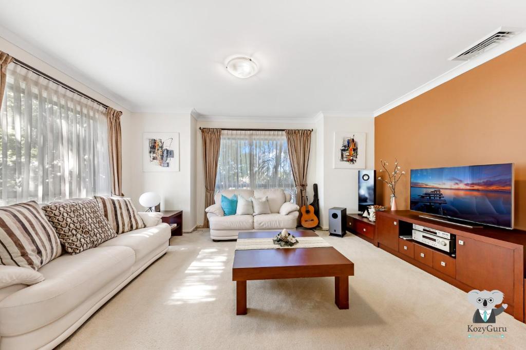 a living room with a couch and a tv at KOZYGURU | Westleigh | Spacious Home with 4 Beds in Thornleigh