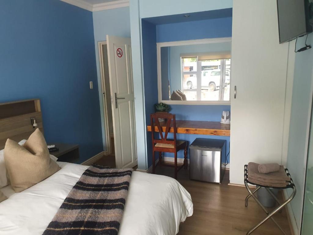 um quarto com uma cama e uma parede azul em Outeniqua Inn em George