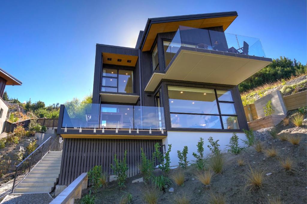 a modern house with glass windows and a balcony at The Villa Lookout - Queenstown Holiday Villa in Queenstown