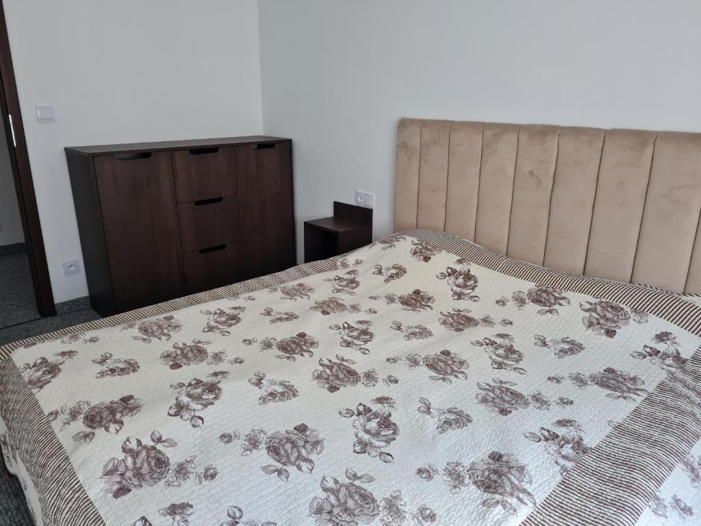 a bed with a blanket on it with a dresser at Apartament Centrum 3 Maja in Mikołajki