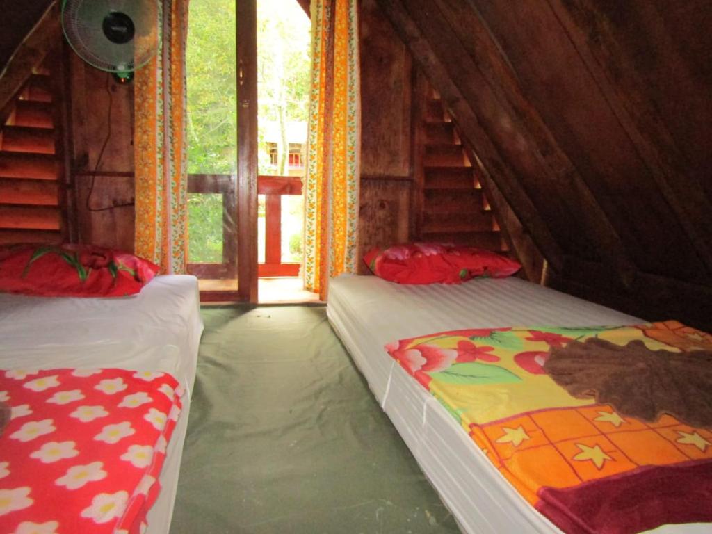 2 camas individuales en una habitación con ventana en Balian Camp penginapan, en Tuk Tuk