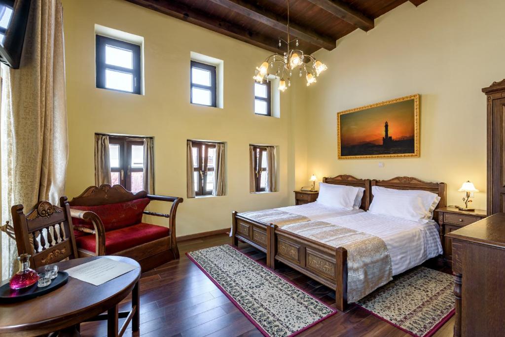 a bedroom with a bed and a chair and a table at Porto Del Colombo Traditional Boutique Hotel in Chania
