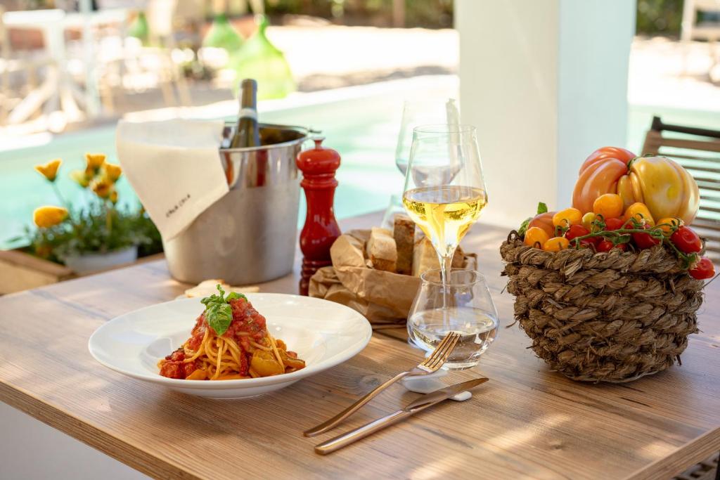 a table with a plate of pasta and a glass of wine at Cala Cala Rooms,Restaurant & Farm Experience in Procida