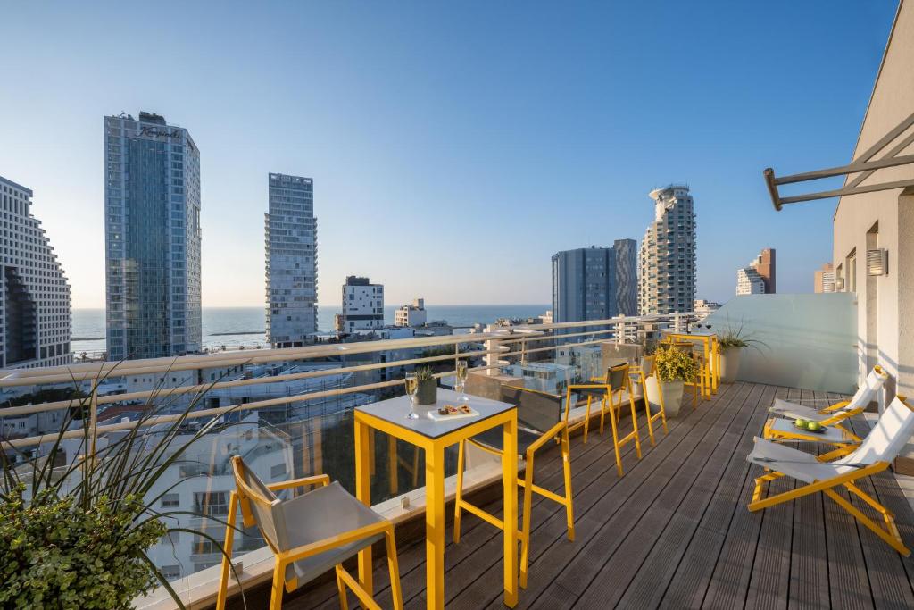 einen Balkon mit Tischen und Stühlen auf einem Gebäude in der Unterkunft BY14 TLV Hotel in Tel Aviv