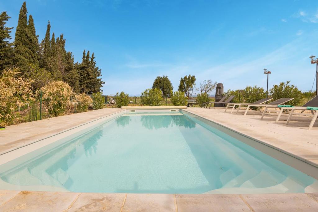 una piscina de agua azul y 2 sillas en Villa les cigales, en Ouveillan