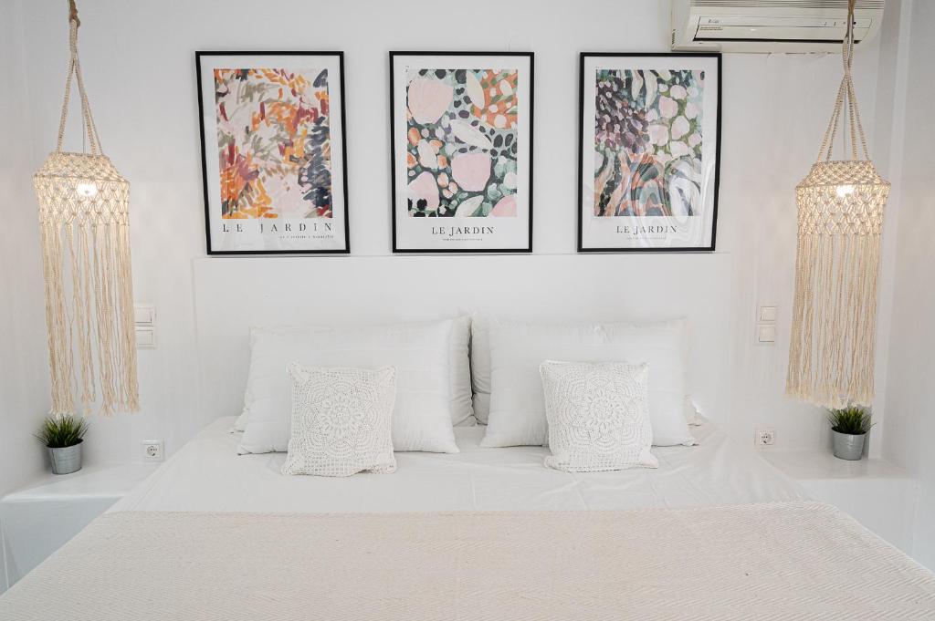 1 dormitorio con 1 cama blanca y 4 cuadros en la pared en Camo’s house, en Poros