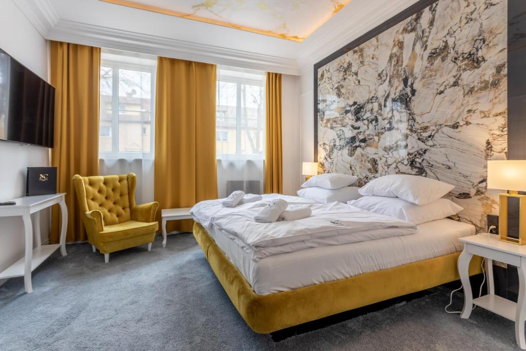 1 dormitorio con 1 cama grande y 1 silla amarilla en Monte Carlo Boutique Hotel, en Świnoujście