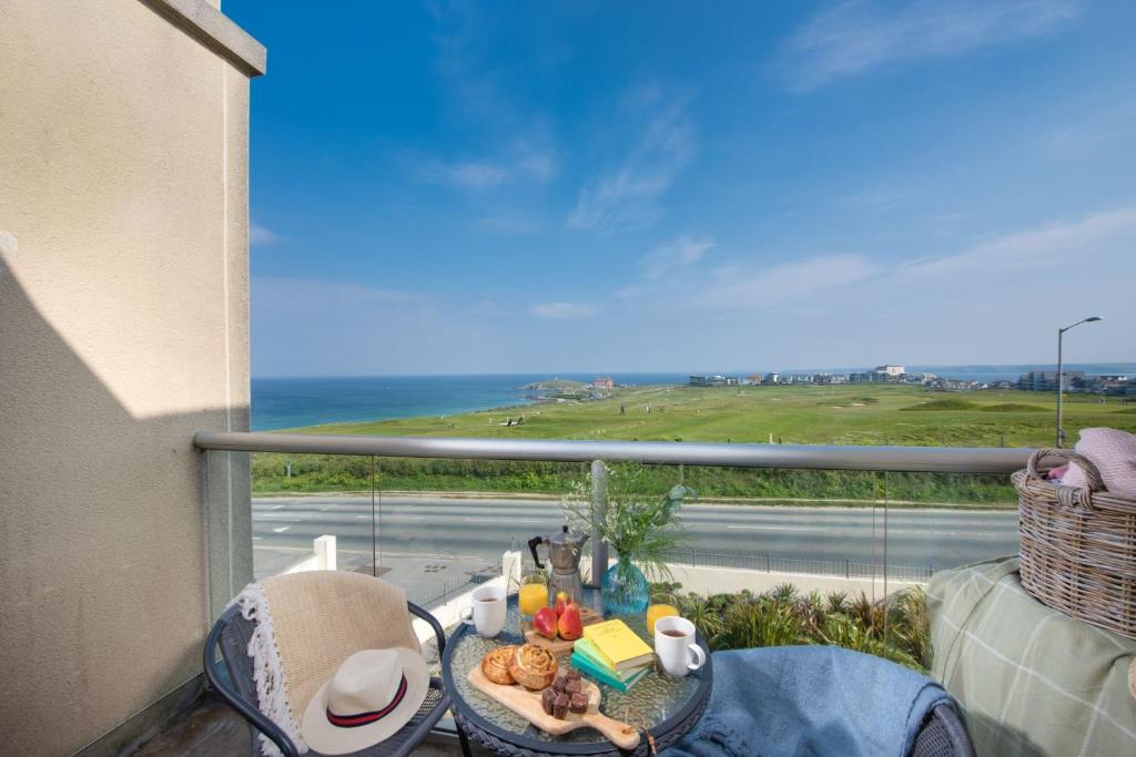 a table and chairs on a balcony with a view of the ocean at 5 The Vista, Newquay in Newquay