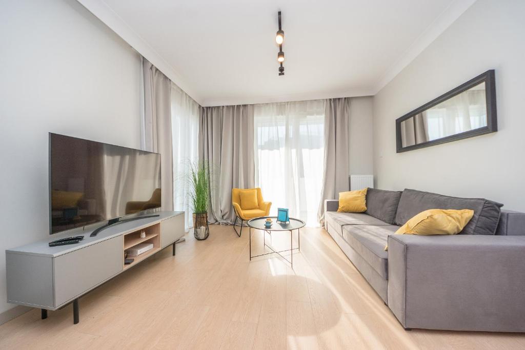 sala de estar con sofá y TV de pantalla plana en Hello Apartments Letnica with sea view and private parking en Gdansk