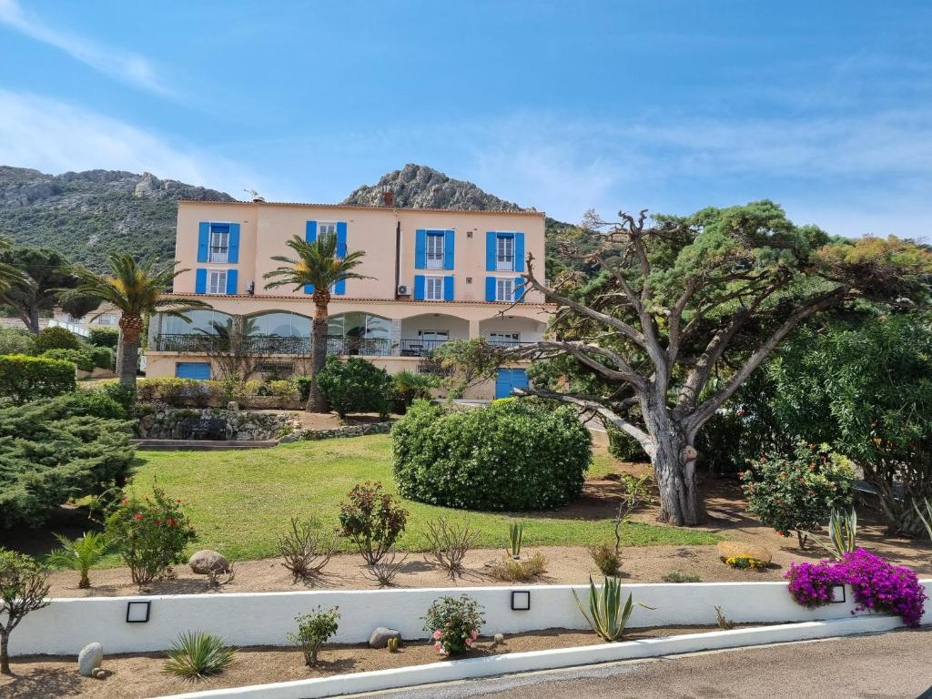 uma casa grande com janelas azuis e árvores em STELLA MARE em Algajola