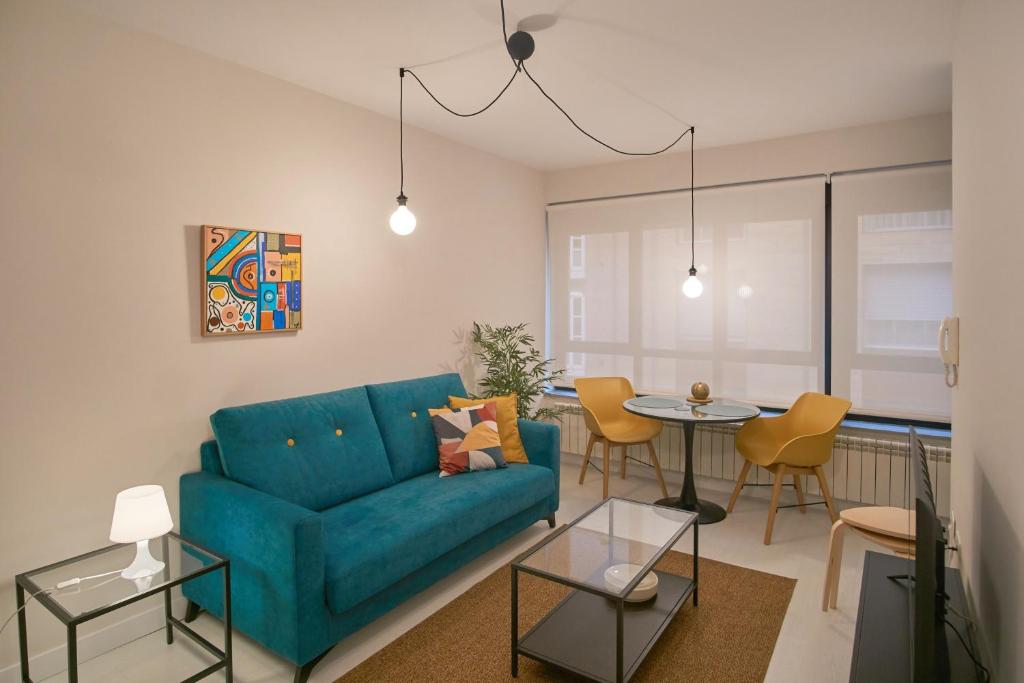 ein Wohnzimmer mit einem blauen Sofa und einem Tisch in der Unterkunft Apartamentos Los Arroyos in Ponferrada