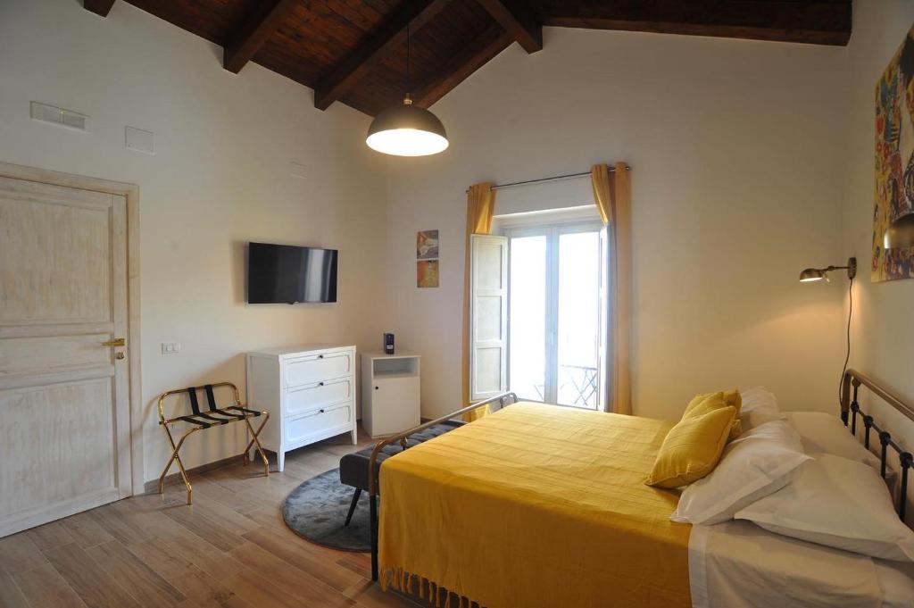 een slaapkamer met een geel bed en een televisie bij La Casa di Nenna in Trentinara
