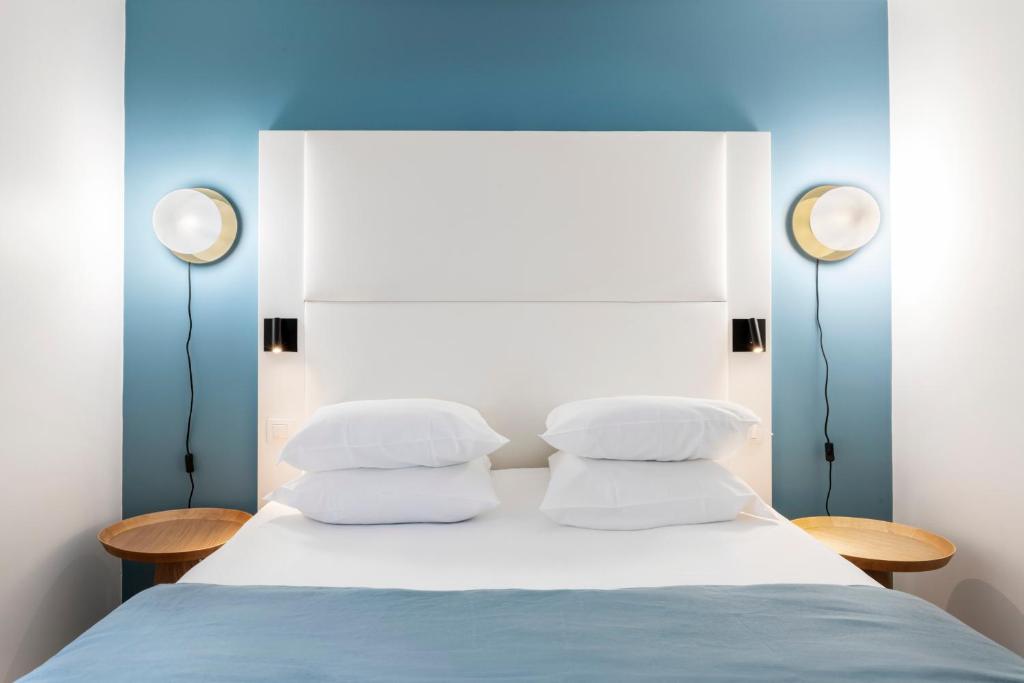 a bed with three pillows and two lights on top at Hôtel Le Windsor Biarritz in Biarritz