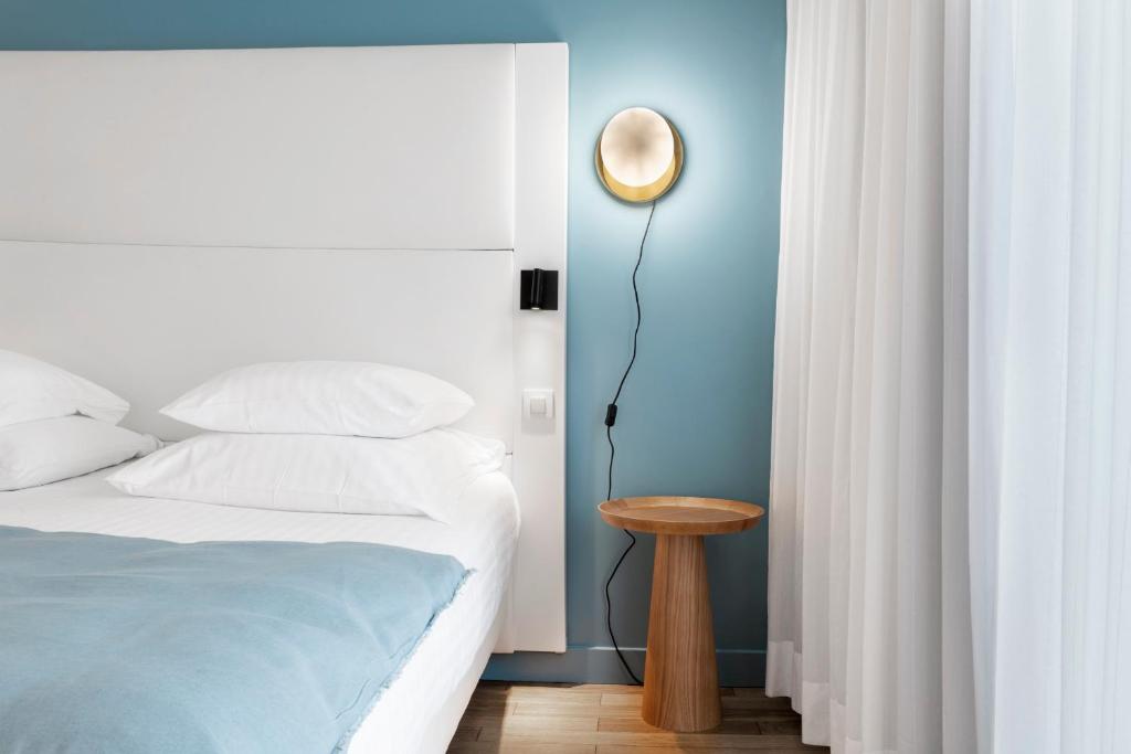 a bedroom with a bed and a table with a lamp at Hôtel Le Windsor Biarritz in Biarritz