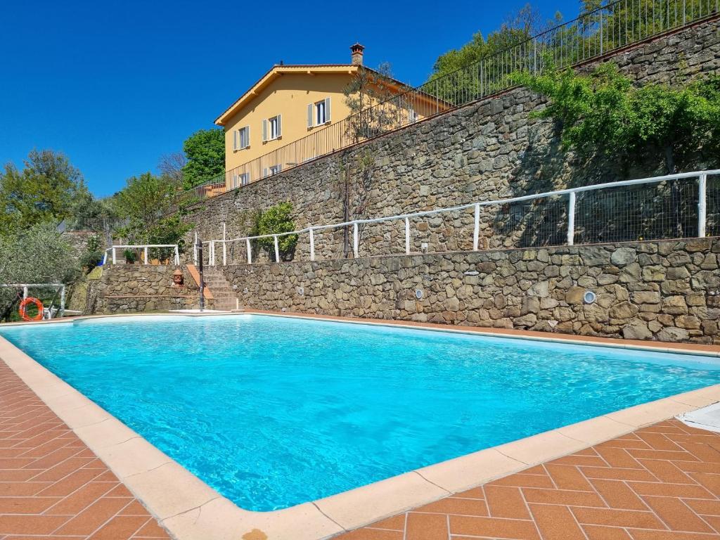 a large blue swimming pool next to a stone wall at Agriturismo La Corte in Pistoia