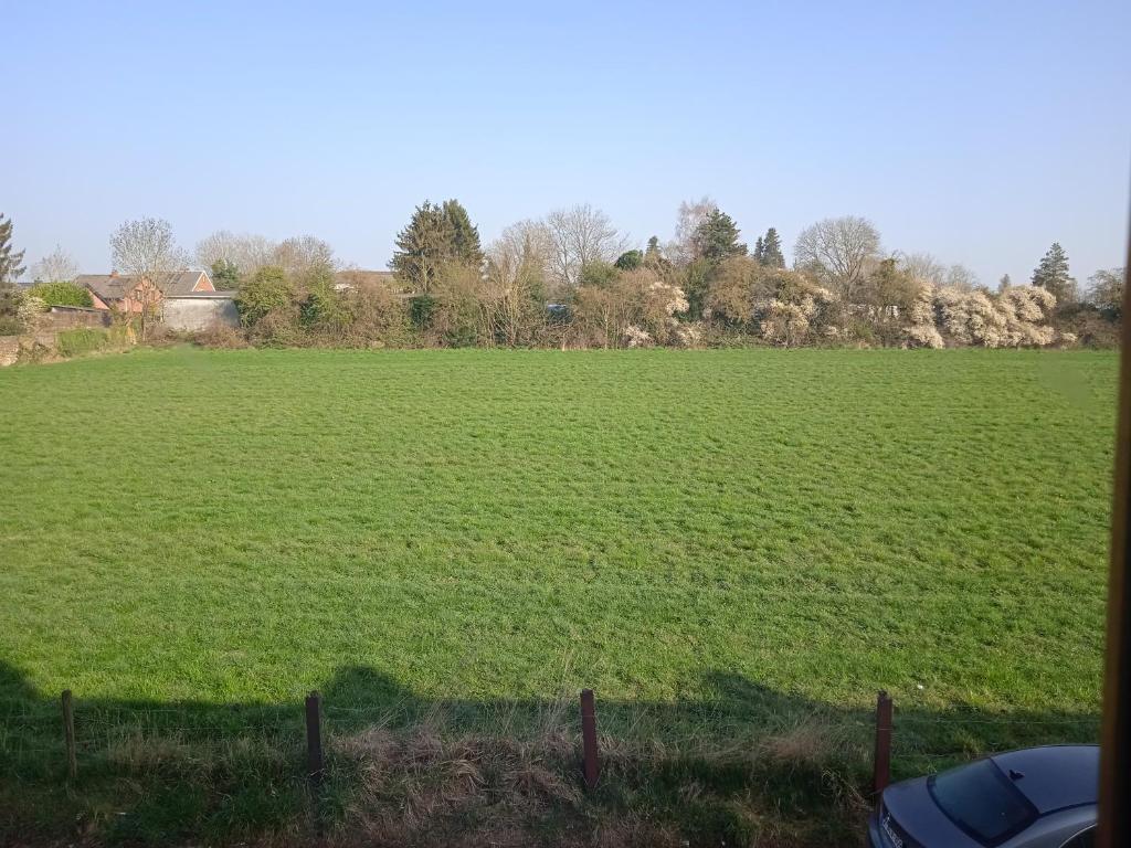 a large field of green grass with a fence at Sweet home vintage in Charleroi