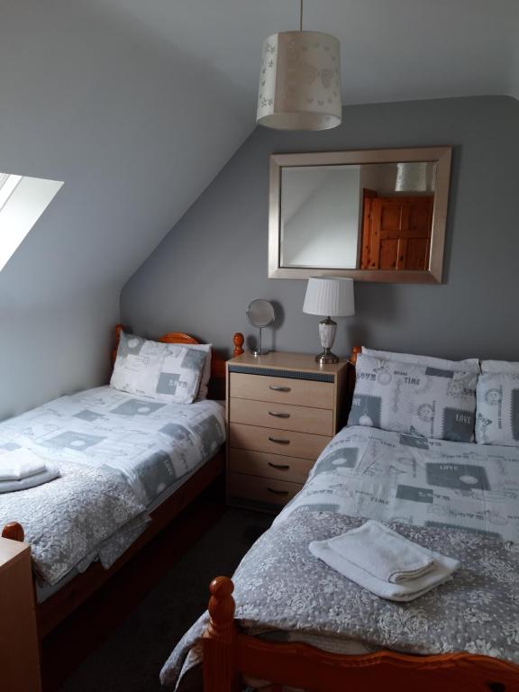 a bedroom with two beds and a dresser and a mirror at Lorna's Apartment Self Catering Holiday Home in Milltown Malbay