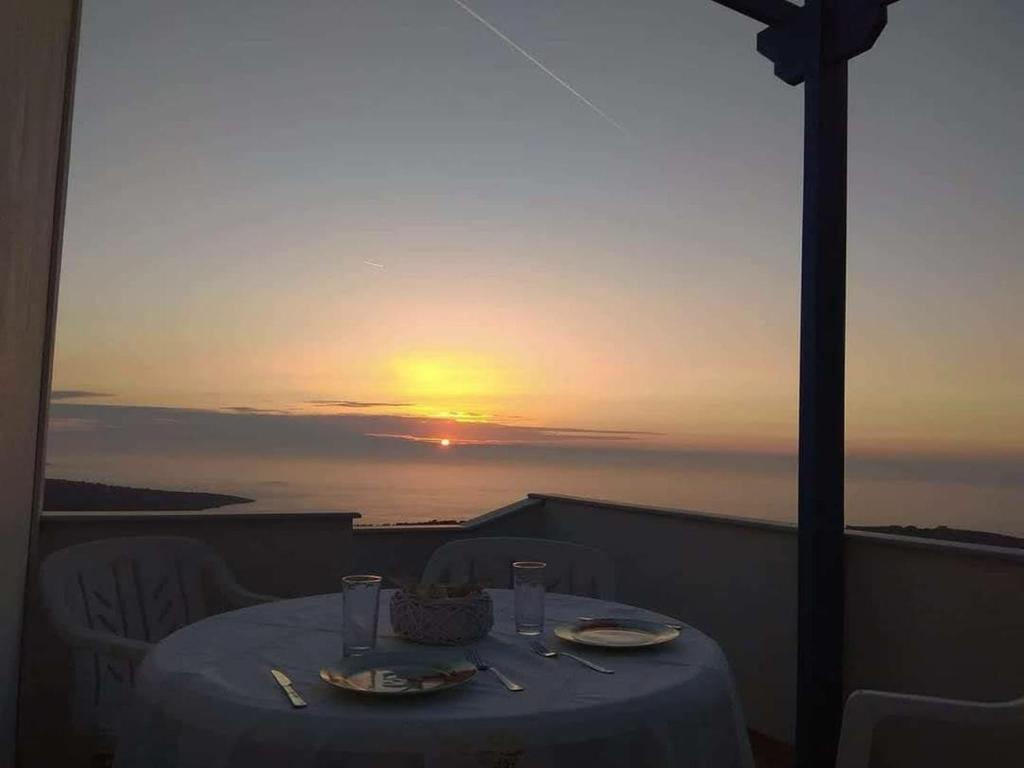 a table on a balcony with the sunset in the background at Mastiha luxury maisonette I in Líthion