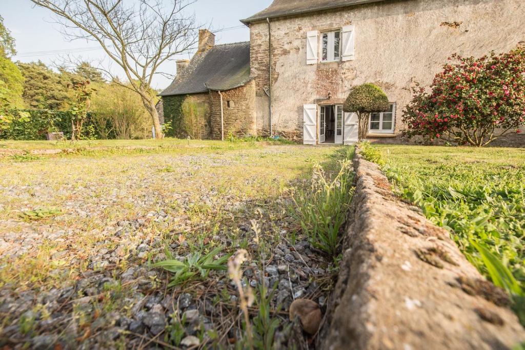 une maison ancienne avec un mur en pierre devant elle dans l'établissement Appartement dans manoir du 17eme, à Pluherlin
