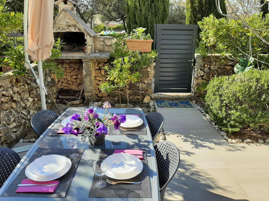 una mesa de comedor con platos y flores en el patio en STUDIO APARTMAN LAURA, GAJAC, PAG, en Novalja