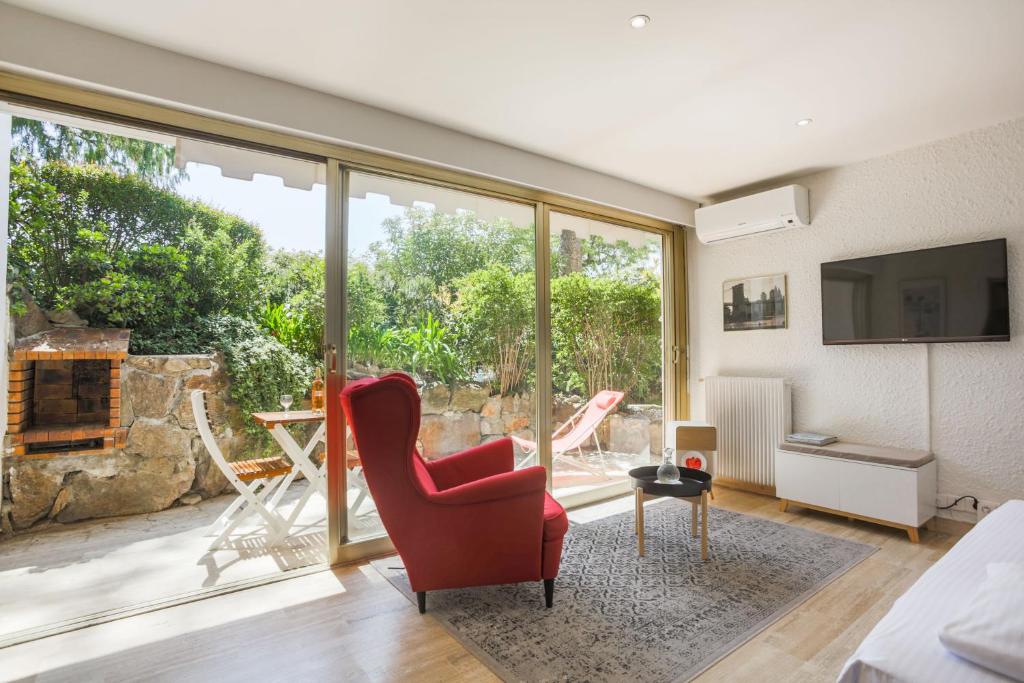 - un salon avec une chaise rouge et une grande fenêtre dans l'établissement Studio A/C La Californie with patio by Olidesi, à Cannes