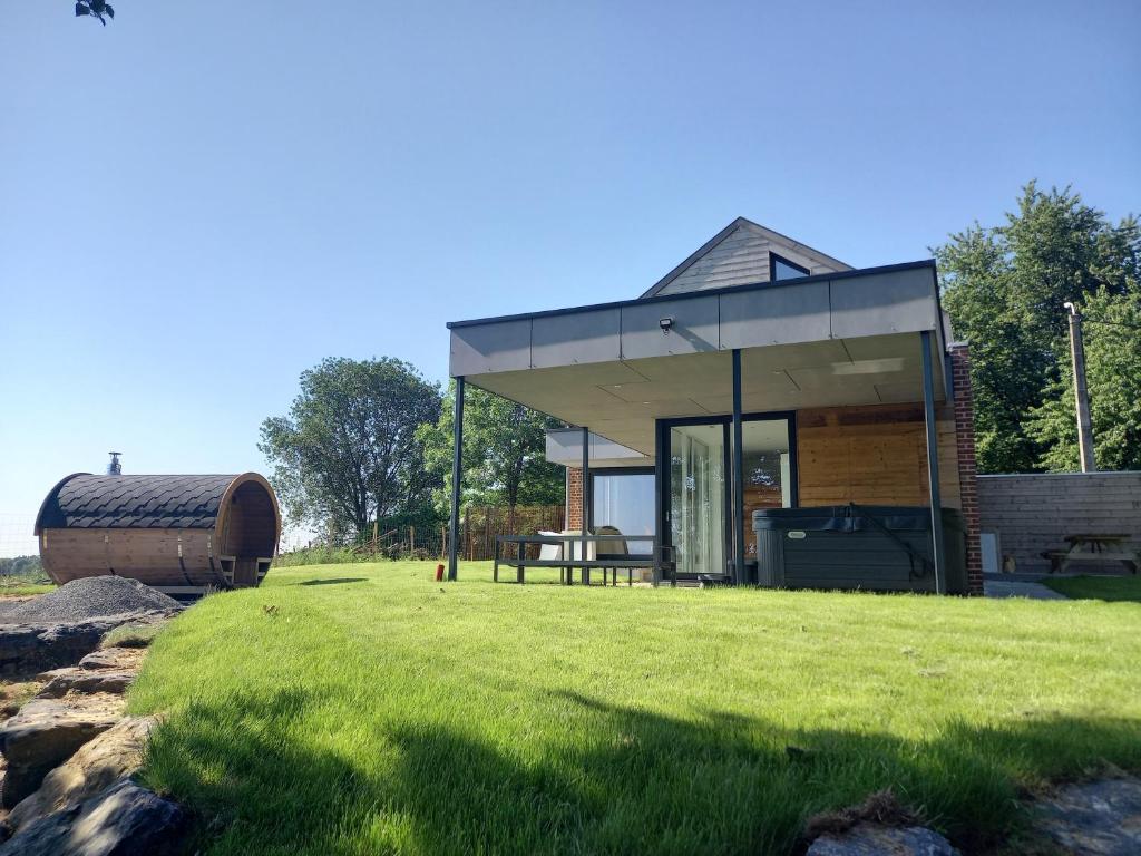 une petite maison avec un toit en verre sur une pelouse dans l'établissement La Rigaudrye, à Ellezelles