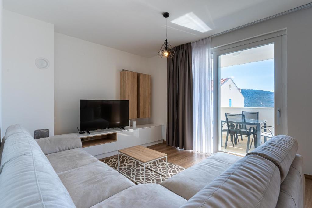 a white living room with a couch and a tv at Sea View Luxury Apartment in Cres
