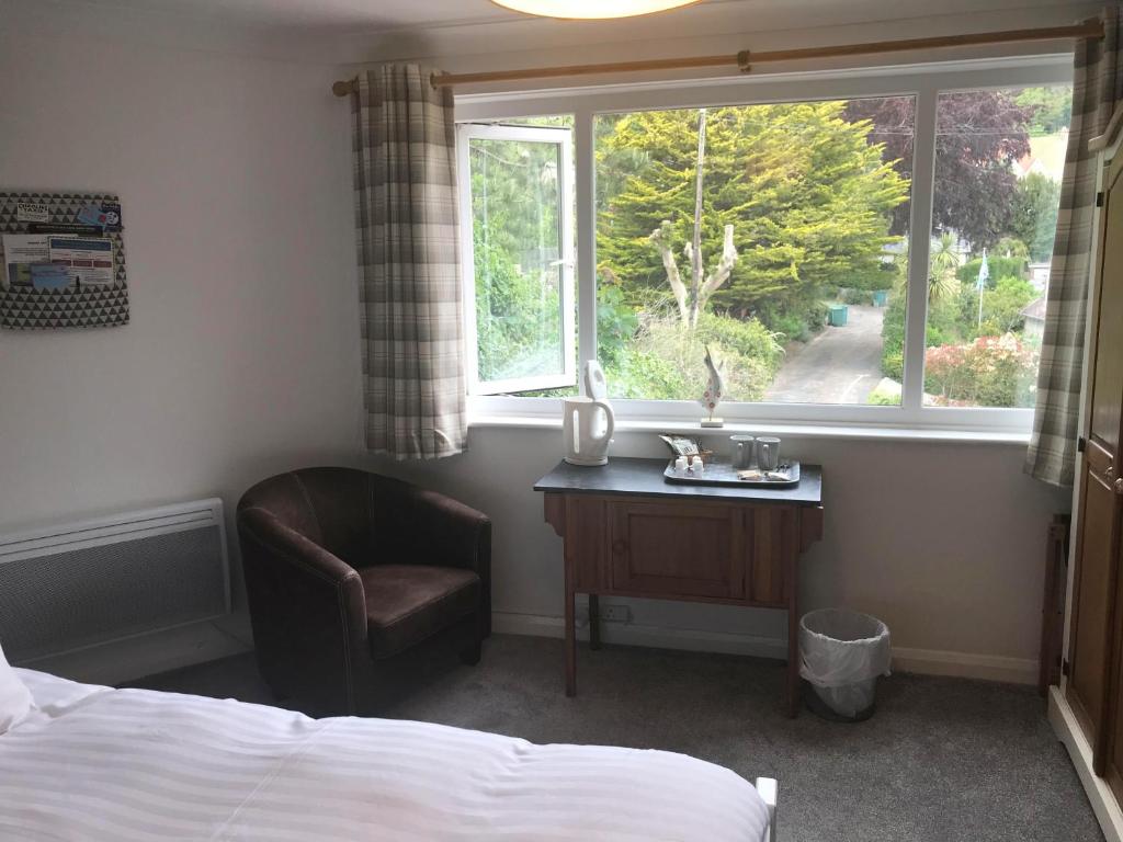 a bedroom with a bed and a chair and a window at Cornerways in Ventnor
