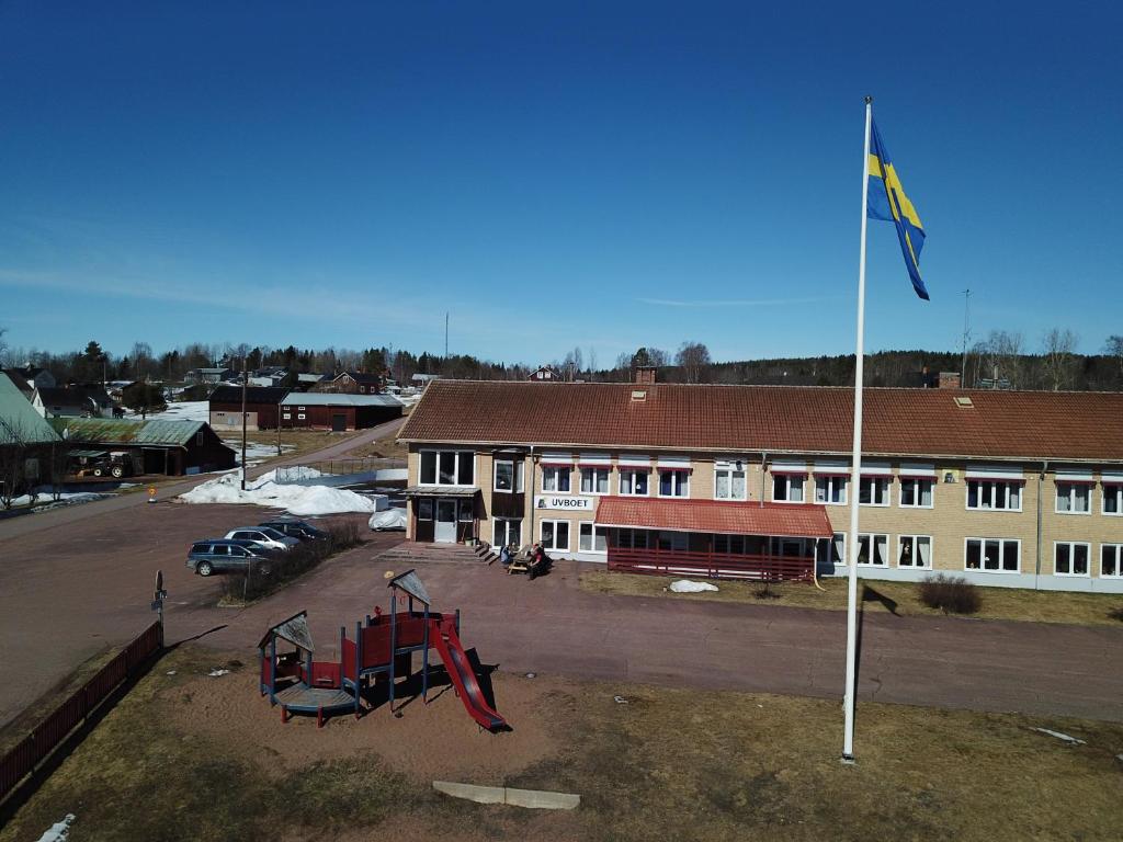 um edifício com um parque infantil e uma bandeira num parque de estacionamento em Åsens Vandrarhem Uvboet em Älvdalen