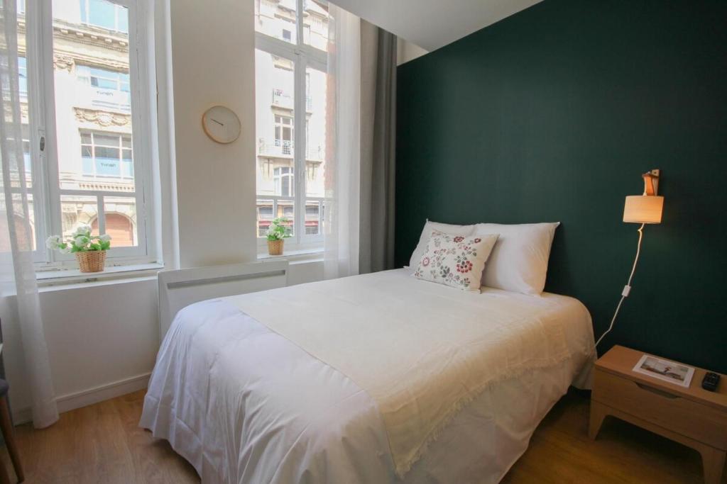 um quarto com uma cama branca e uma parede verde em Lille Grand Place - Nice and equipped studio! em Lille