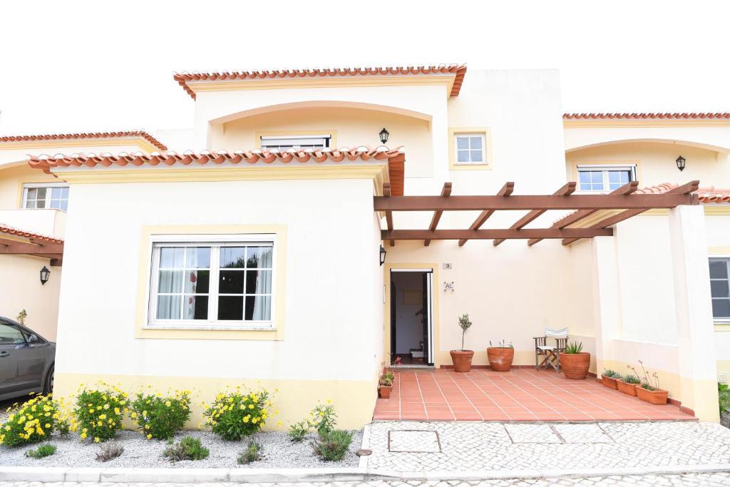 ein weißes Haus mit einer hölzernen Pergola in der Unterkunft Casa Lavanda in Casal da Lagoa Seca