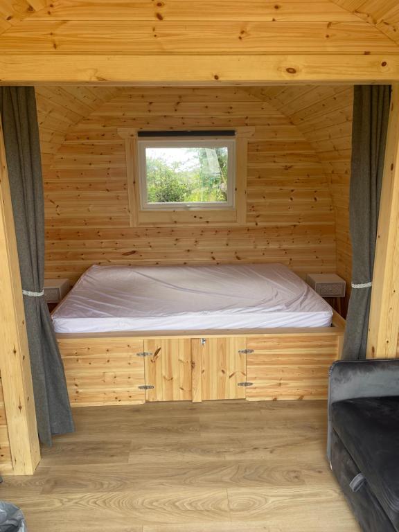Cama en una cabaña de madera con ventana en Wall park touring Centry road camping, en Brixham